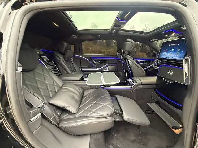 The rear cabin of a Maybach, reclined seat and a table that folds out under a starlit headliner