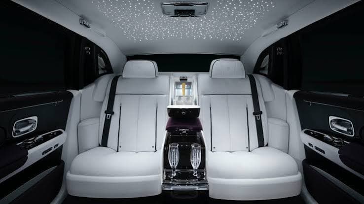 The white leather rear cabin of a luxury saloon, starlight headliner and champagne flutes on the console