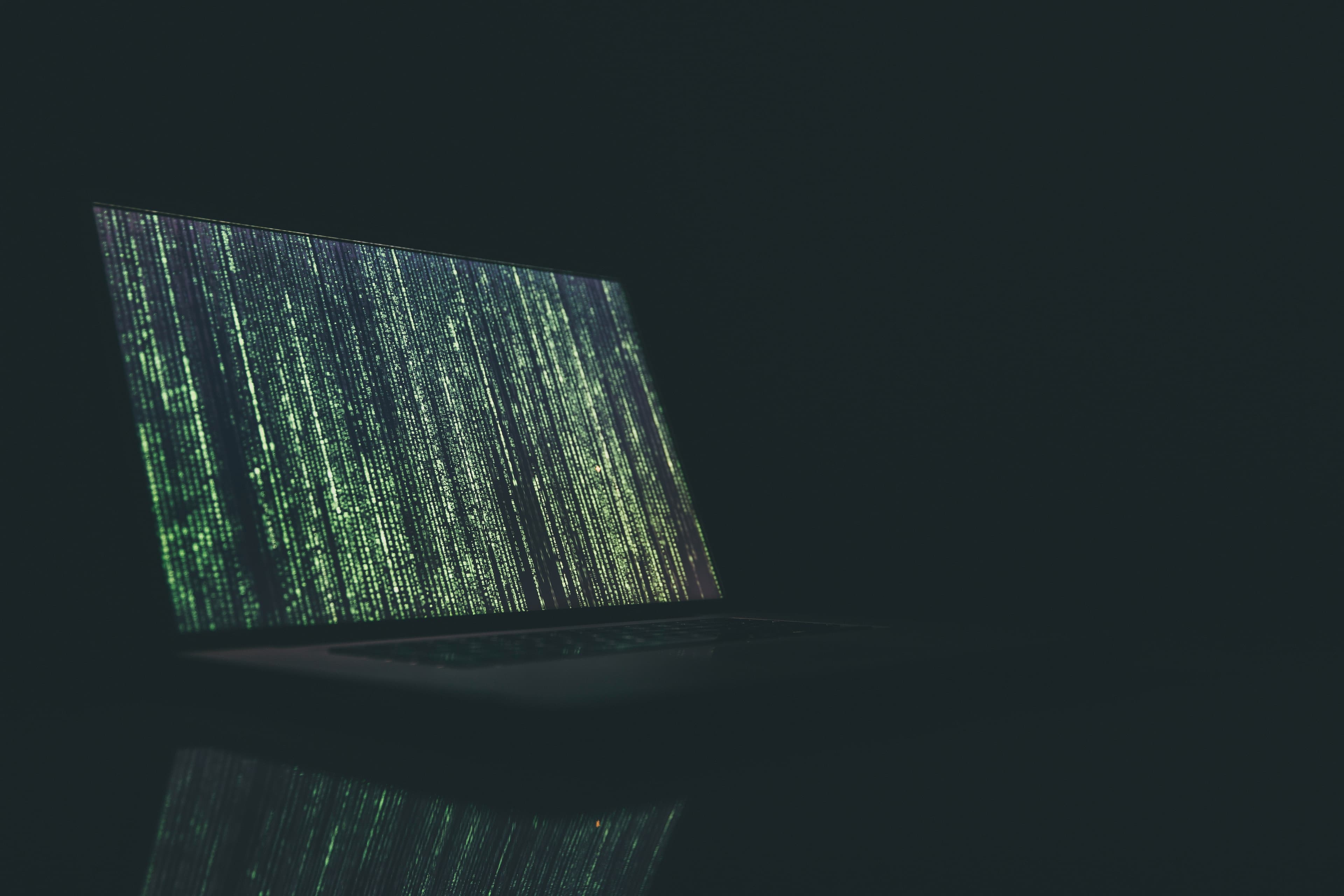 A laptop screen showing lines of code in a darkened room