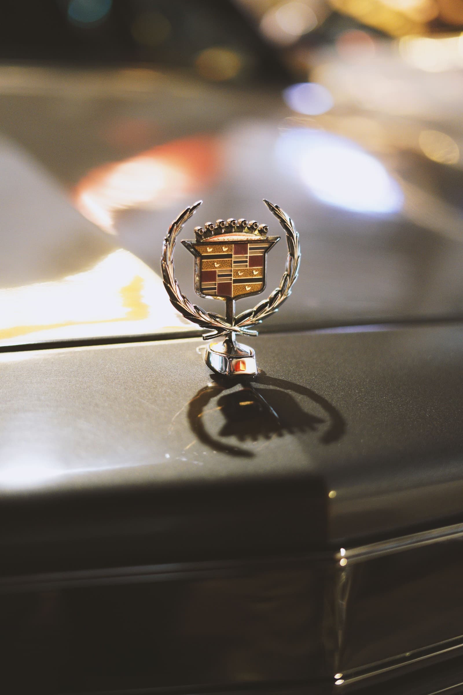 A Cadillac hood ornament, city lights blurred in the background at night