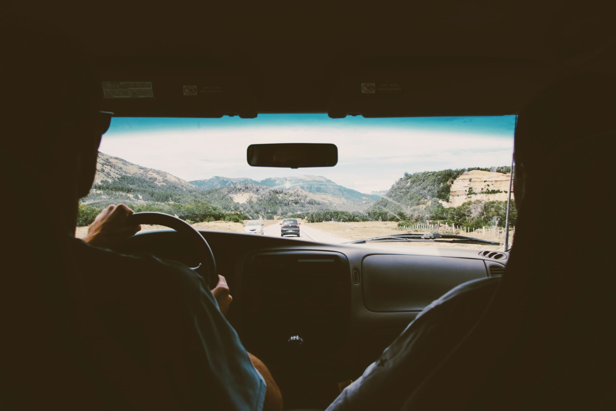The view through a car windscreen, driving toward a mountain range