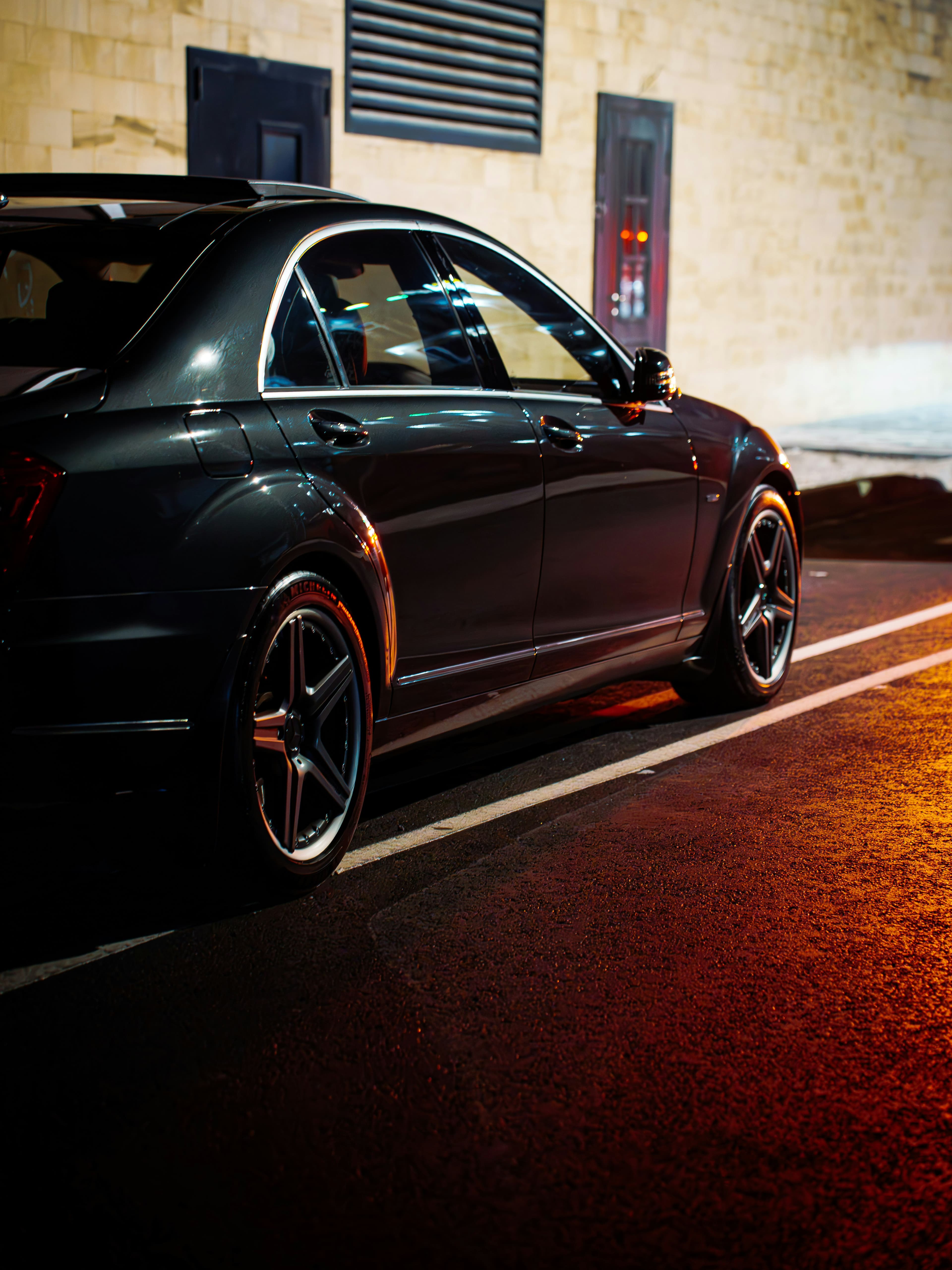 A car parked on a quiet street at night, lit by warm ambient light