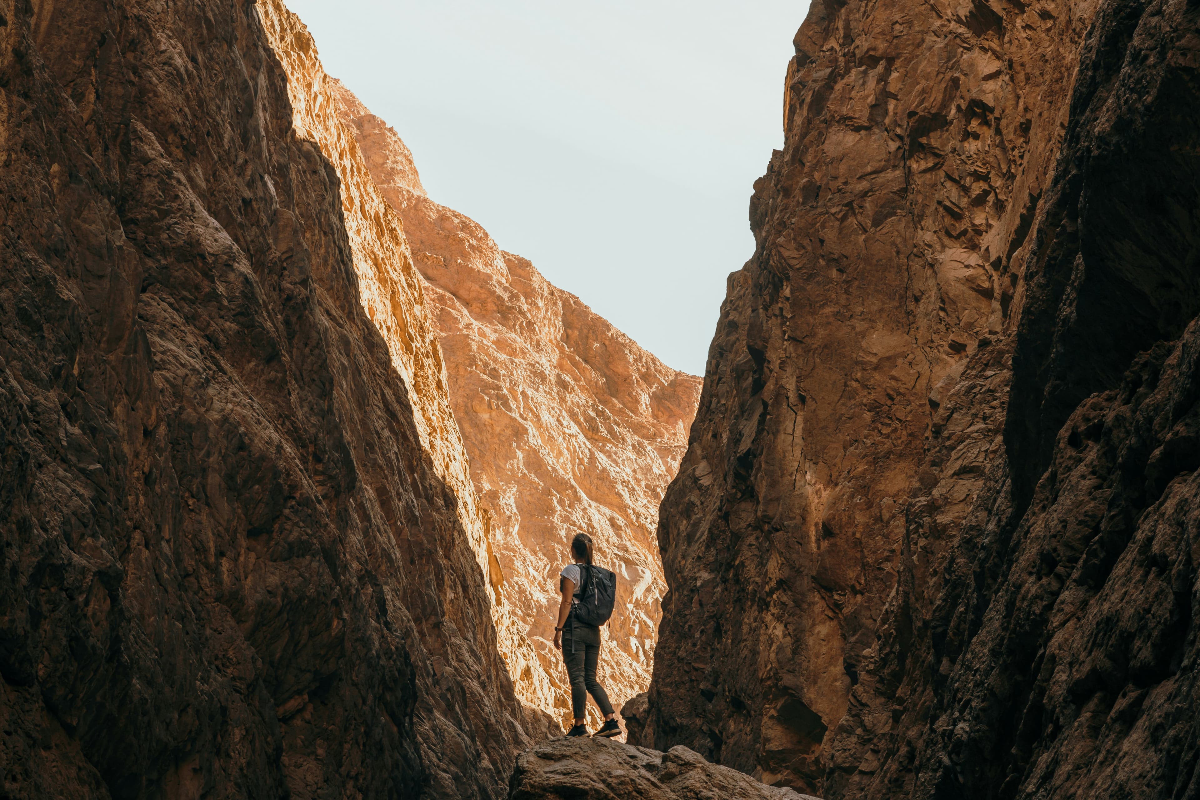 A traveller led through a narrow desert canyon by a local guide